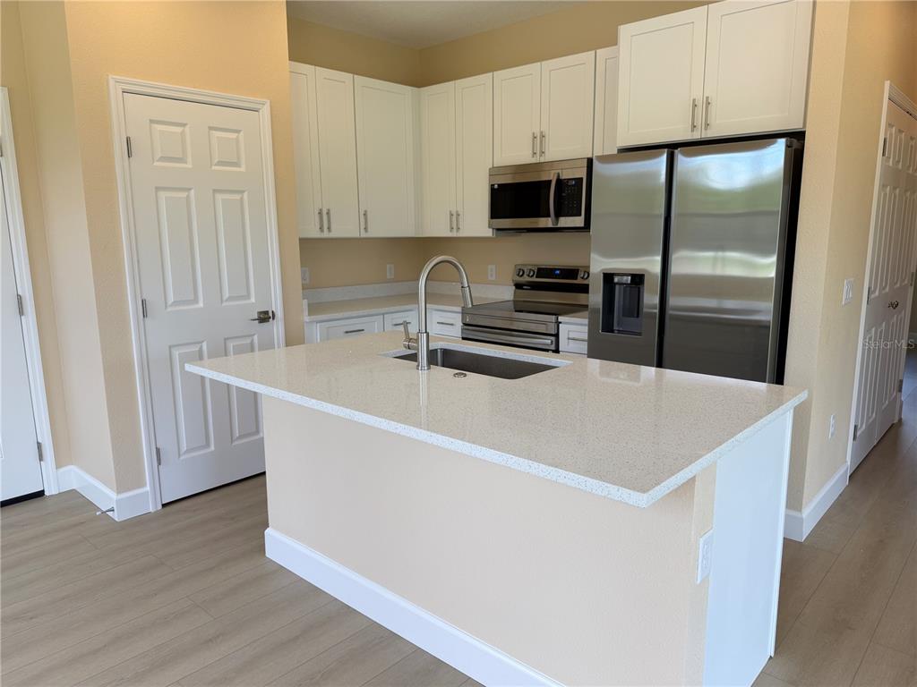 4661 Hickory Tree Road St. Cloud, FL 34772 - Photo 5 of 20 a kitchen with stainless steel appliances a refrigerator a sink a stove a microwave and wooden floors