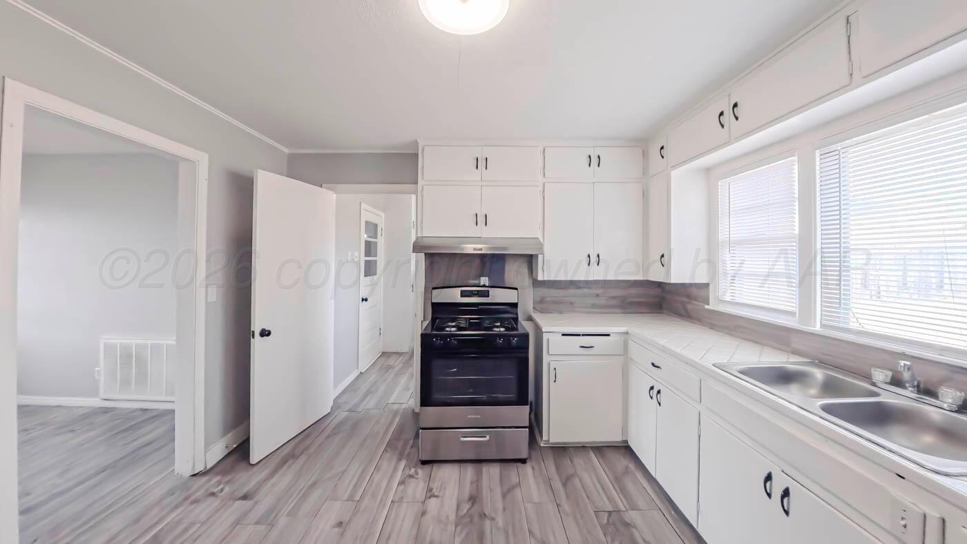 300 North Bryan Street Borger, TX 79007 - Photo 7 of 21 a kitchen with a stove a sink and wooden floor