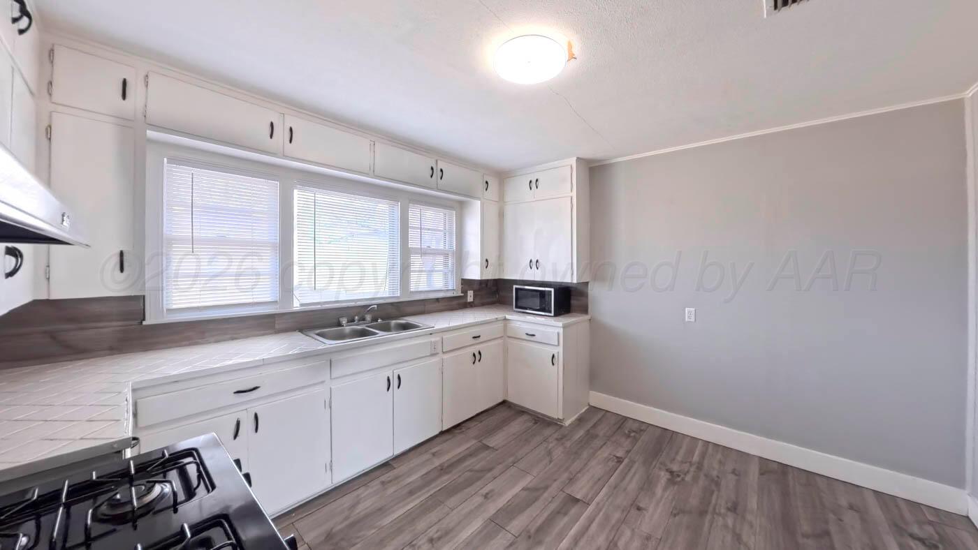 300 North Bryan Street Borger, TX 79007 - Photo 8 of 21 a kitchen with a sink cabinets wooden floor and a window