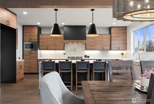 a kitchen with stainless steel appliances kitchen island granite countertop a table chairs in it and wooden floors