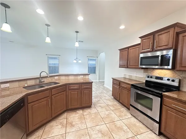 a large kitchen with stainless steel appliances granite countertop a sink and cabinets