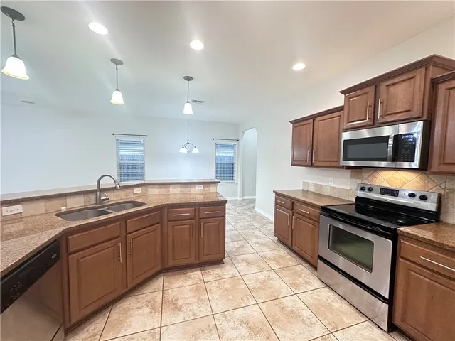 a large kitchen with stainless steel appliances granite countertop a sink and cabinets