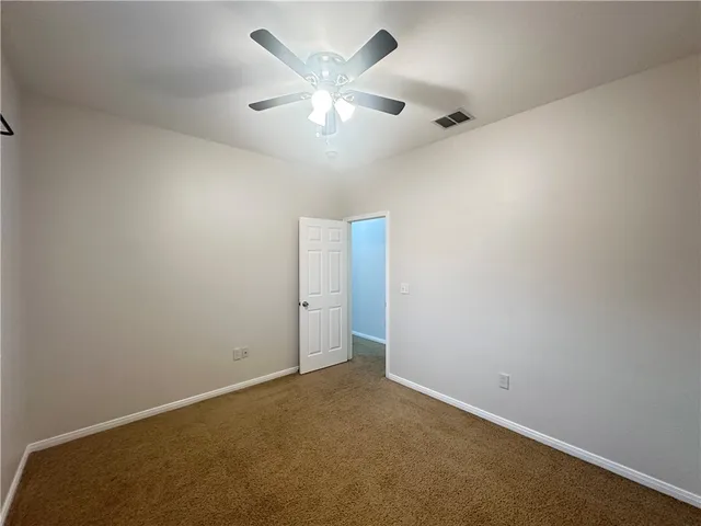 an empty room with a ceiling fan and wooden floor