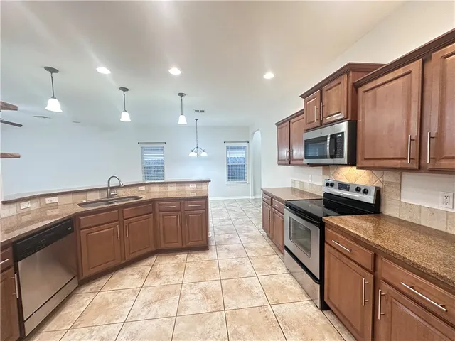 a large kitchen with granite countertop a stove top oven microwave and cabinets