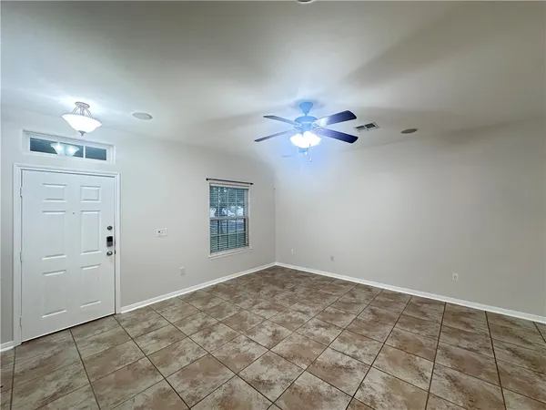 a view of an empty room with chandelier fan