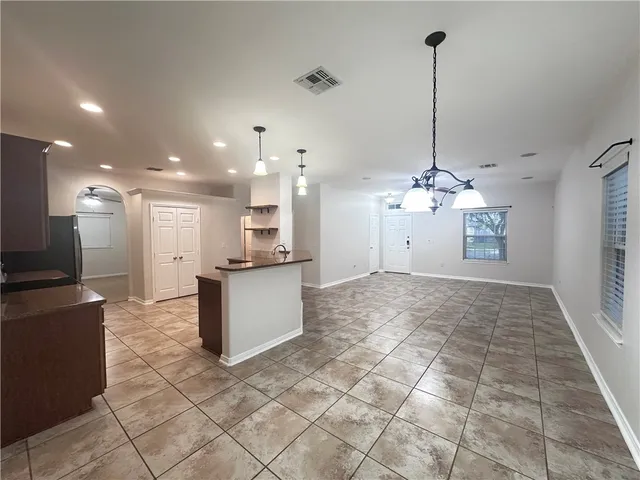 a large kitchen with kitchen island a island a stove a counter space and a view of living room