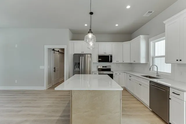 a kitchen with stainless steel appliances a sink a stove a refrigerator cabinets and wooden floor