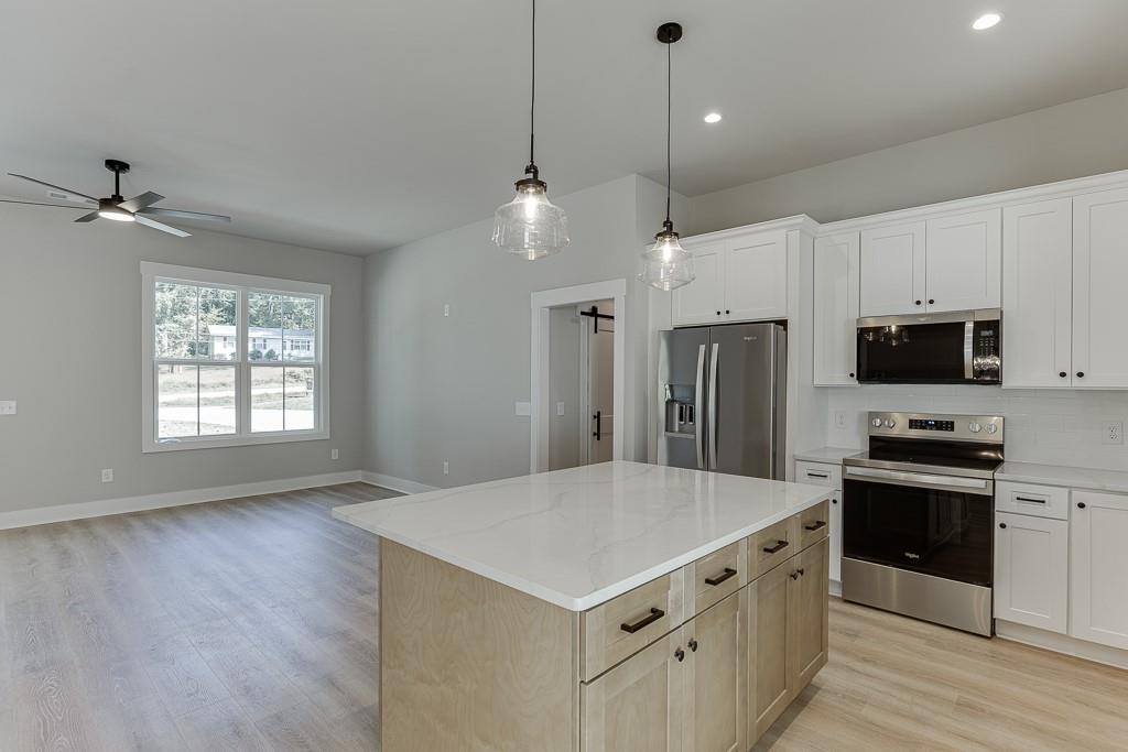 125 Rains Road Jefferson, GA 30549 - Photo 12 of 43 a kitchen with stainless steel appliances a sink a stove a refrigerator cabinets and wooden floor