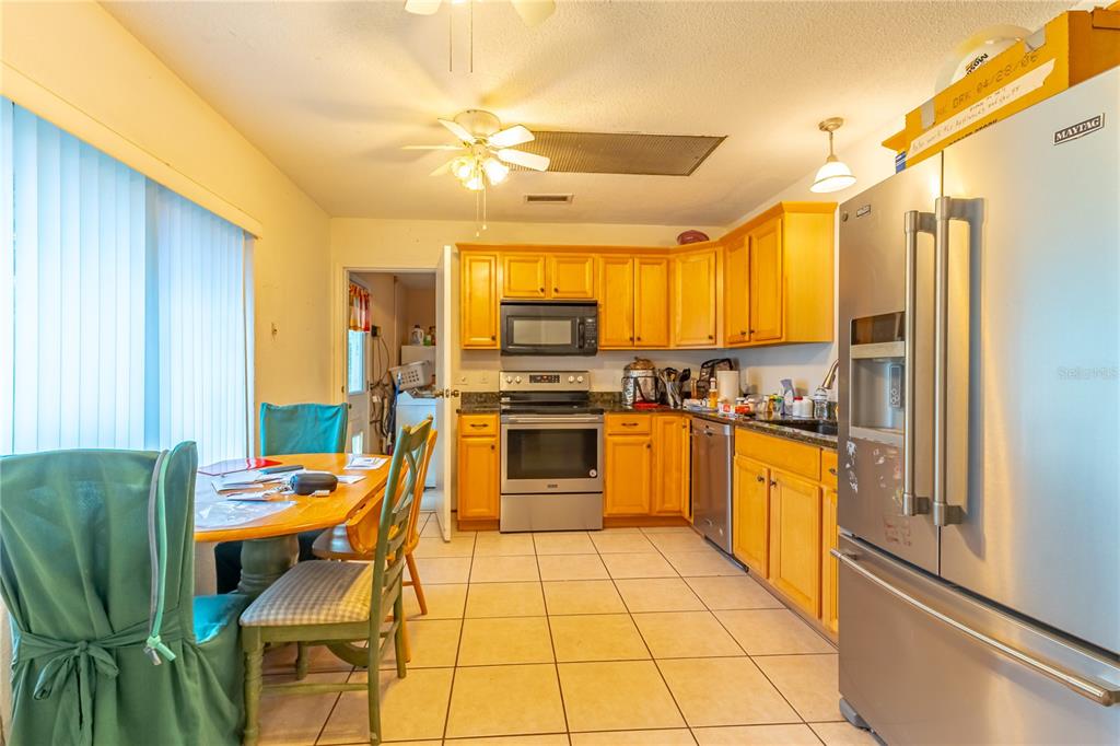 9349 Edison Road Lithia, FL 33547 - Photo 13 of 27 a kitchen with stainless steel appliances granite countertop a stove top oven a sink dishwasher and a refrigerator with wooden floor