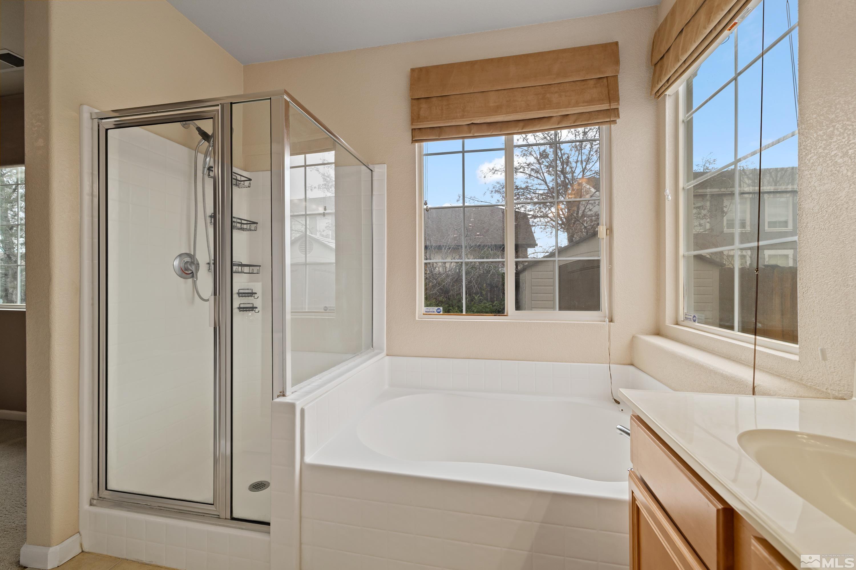 8900 Sorcha Street Reno, NV 89506 - Photo 18 of 39 a bathroom with a granite countertop sink and a bathtub next to a window