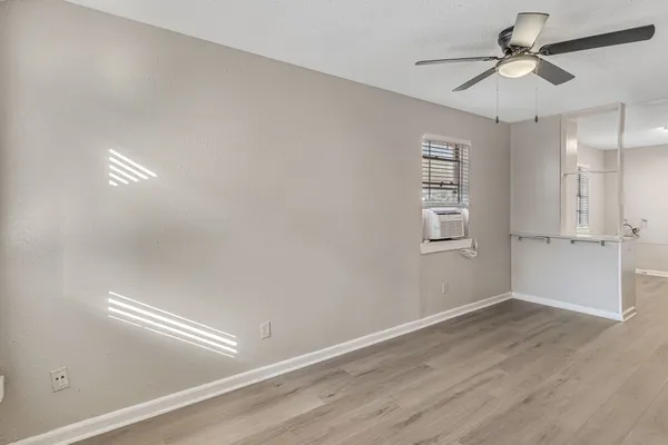 a view of empty room with wooden floor and fan