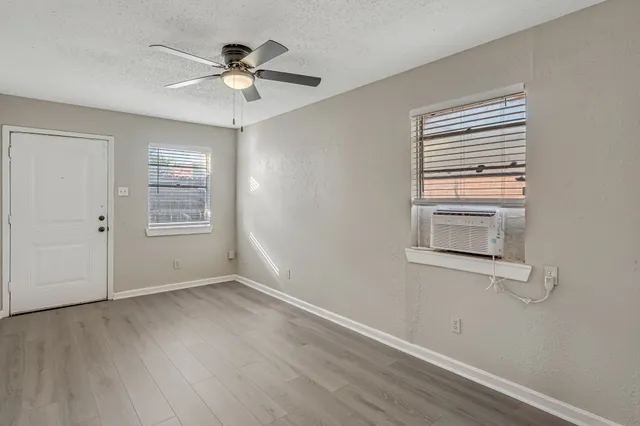 a view of an empty room with a window and wooden floor