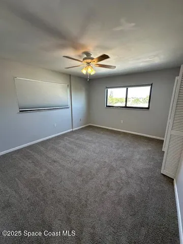 a view of an empty room with a chandelier fan