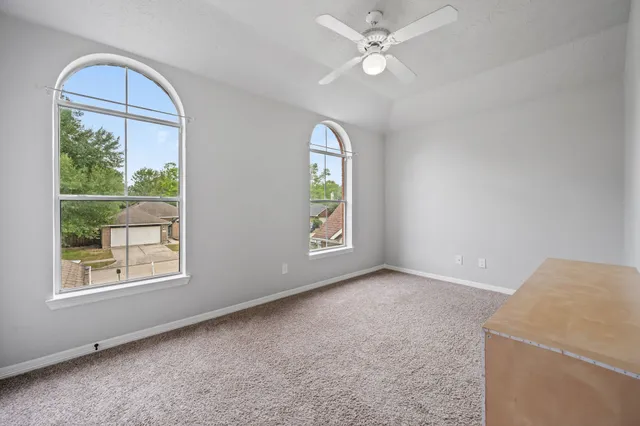 an empty room with windows and chandelier fan