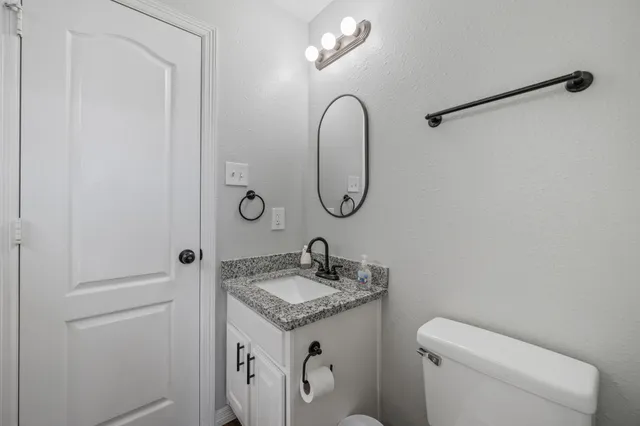 a bathroom with a granite countertop sink a toilet and a mirror
