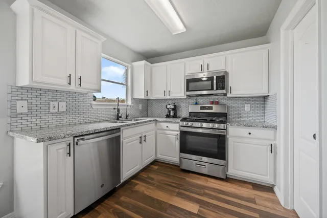a kitchen with stainless steel appliances granite countertop a stove sink and microwave