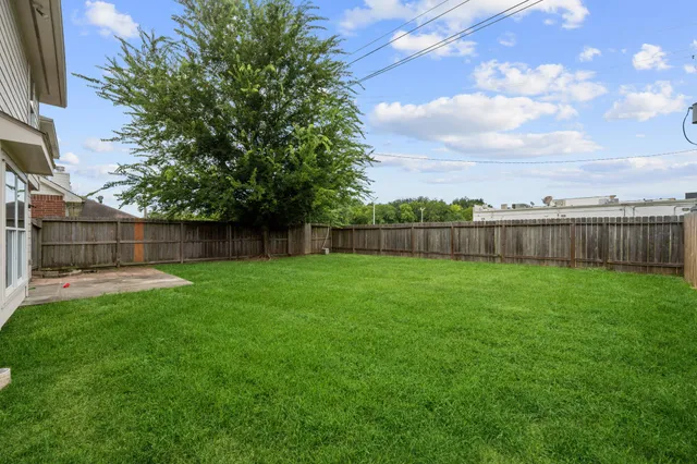 a view of a backyard with grass and a fence