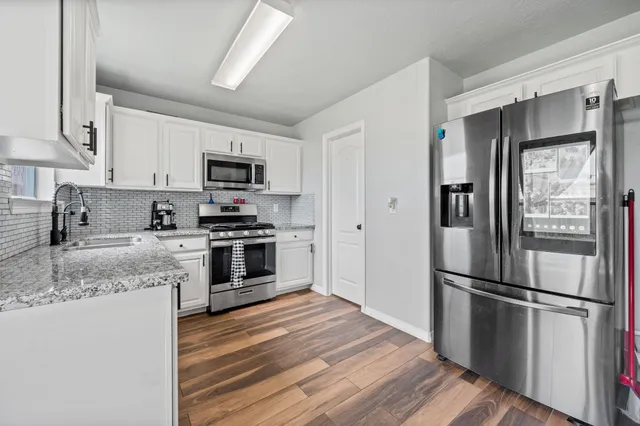 a kitchen with granite countertop a refrigerator stove and sink