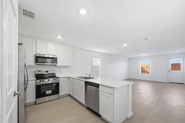 a kitchen with stainless steel appliances granite countertop a stove a sink and a refrigerator