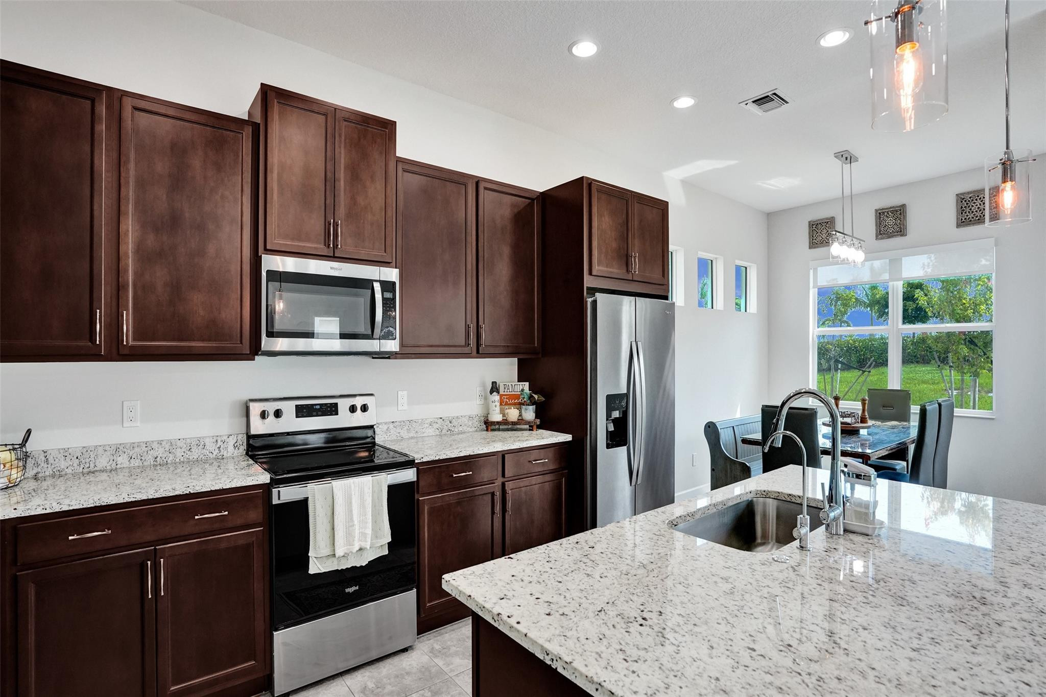 5416 Macoon Way Loxahatchee, FL 33470 - Photo 10 of 43 a kitchen with stainless steel appliances granite countertop a refrigerator a stove top oven a sink dishwasher and wooden cabinets with granite countertops