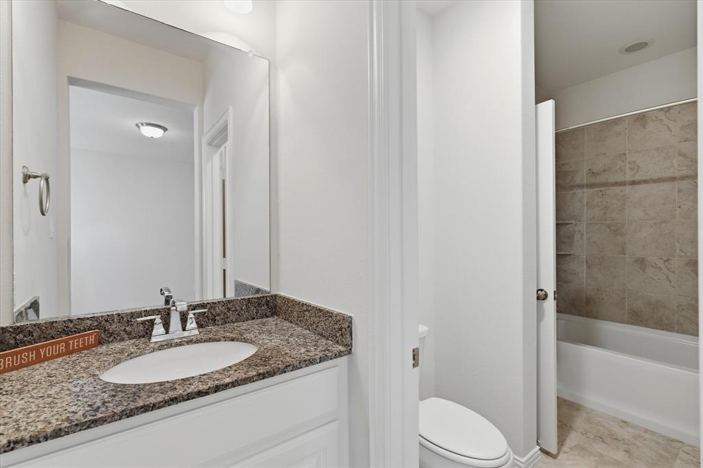 2433 Mare Road Carrollton, TX 75010 - Photo 25 of 37 Jack and Jill Bathroom featuring a vanity with a granite countertop, undermount sink, and chrome fixtures with a tub/shower combo