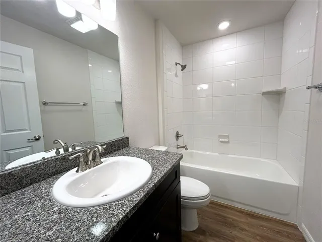 a bathroom with a granite countertop sink toilet a mirror and bathtub