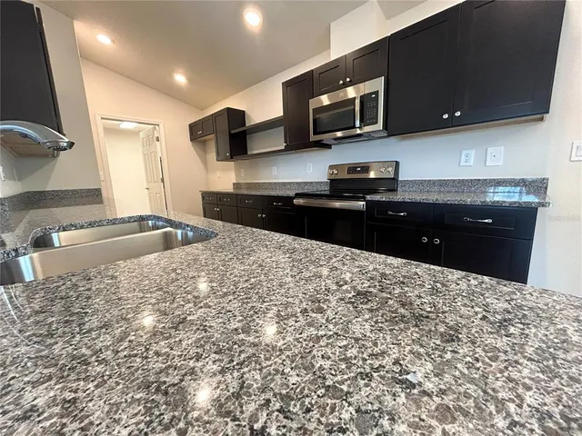 a kitchen with stainless steel appliances kitchen island granite countertop a stove a sink and a microwave