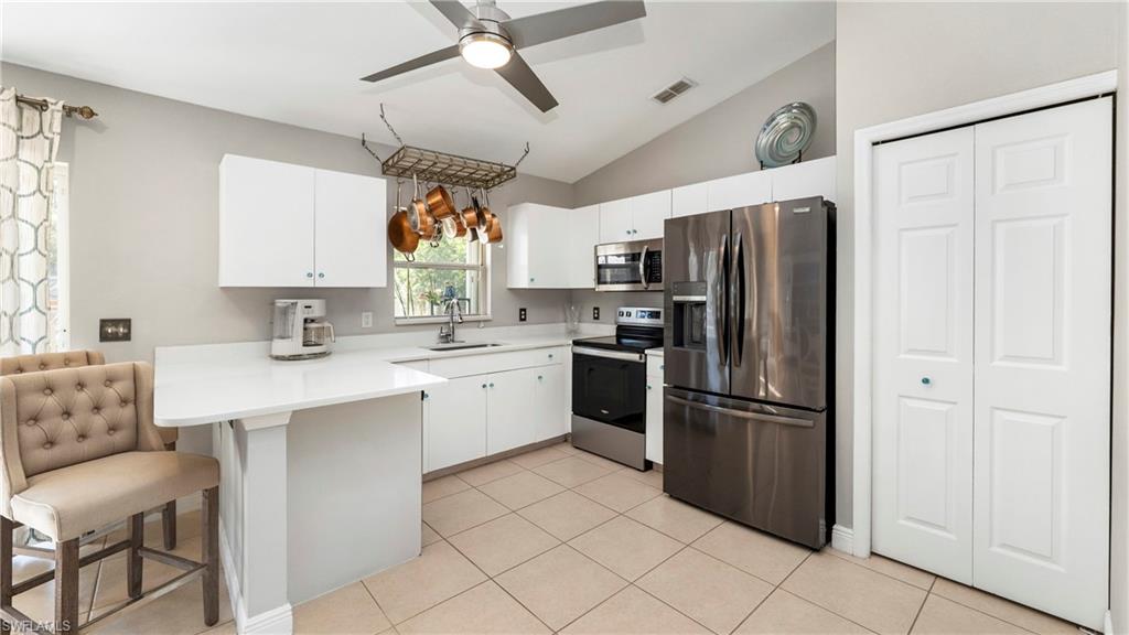 3340 2nd Avenue Southeast Naples, FL 34117 - Photo 3 of 24 a kitchen with a refrigerator a sink dishwasher a stove and white cabinets