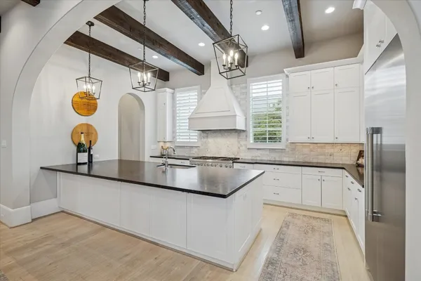 a kitchen with granite countertop a sink a stove and cabinets