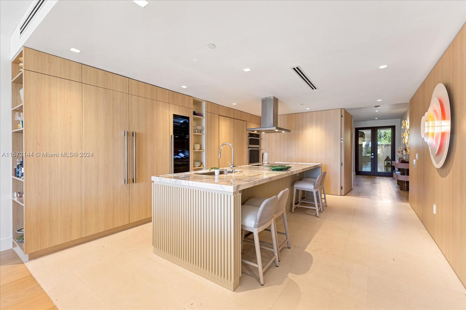 2113 Fisher Island Drive, Unit 2113 Miami Beach, FL 33109 - Photo 13 of 49 a kitchen with stainless steel appliances kitchen island granite countertop a refrigerator a stove a sink dishwasher with a dining table and chairs