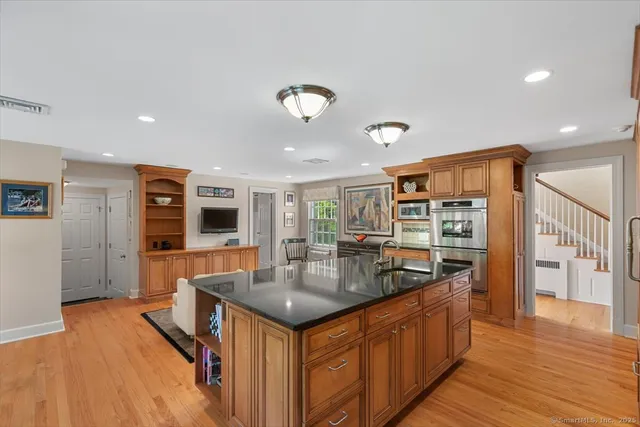 a kitchen with stainless steel appliances granite countertop a sink a stove and a wooden floors