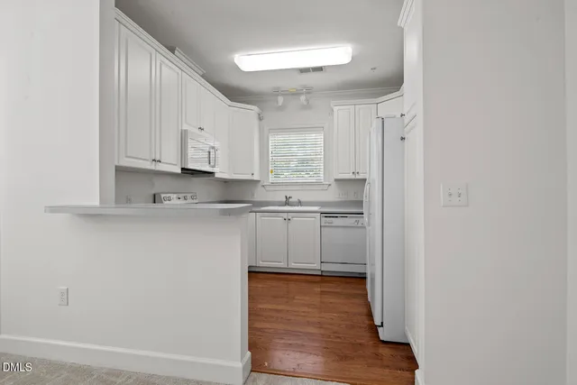 a view of a livingroom with a kitchen and chandelier fan