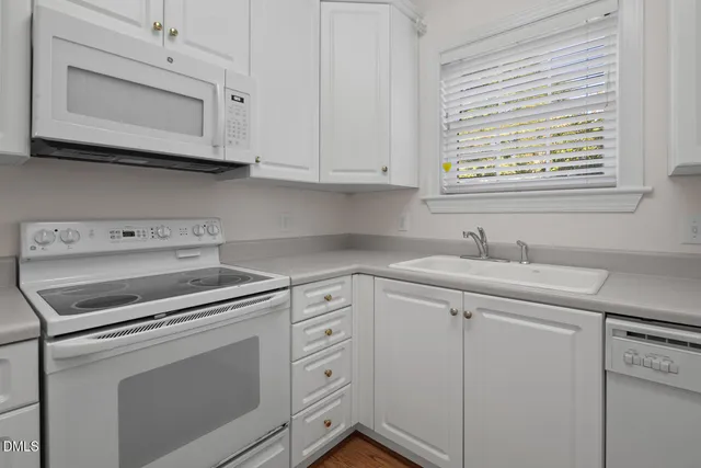 a kitchen with white cabinets white appliances and sink