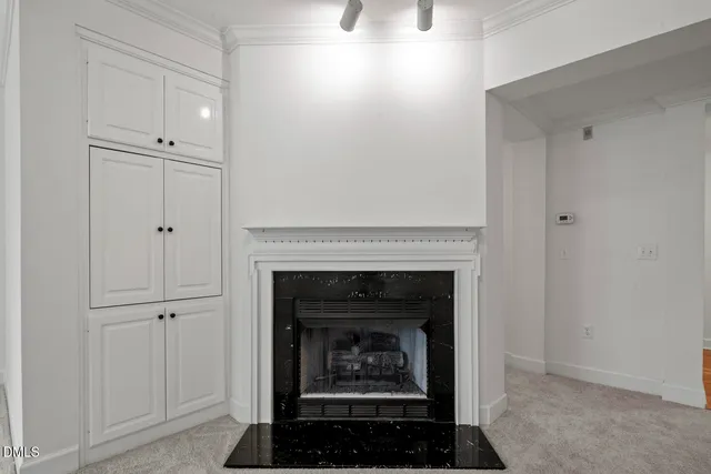 a view of an empty room with chandelier fan and fire place