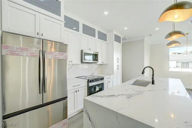 a kitchen with stainless steel appliances granite countertop a refrigerator a stove and a sink with wooden floor