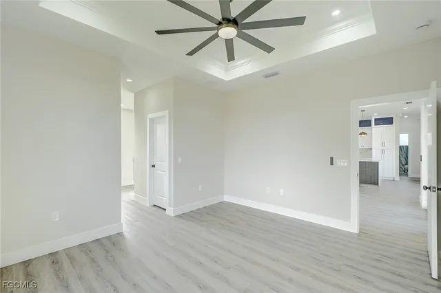 an empty room with wooden floor and ceiling fan