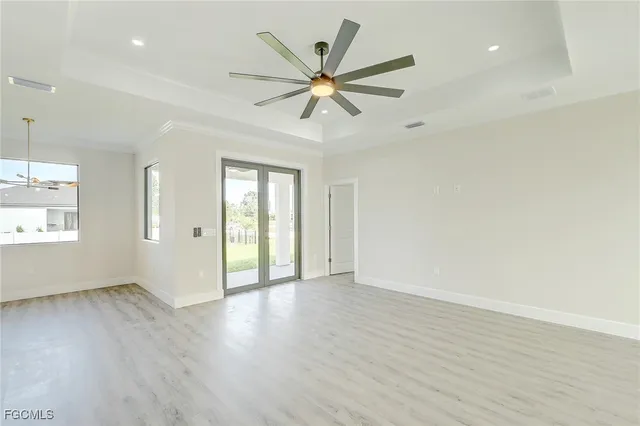 an empty room with wooden floor fan and windows