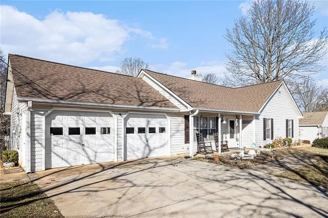a view of a white house with large windows and a table and chairs under an umbrella