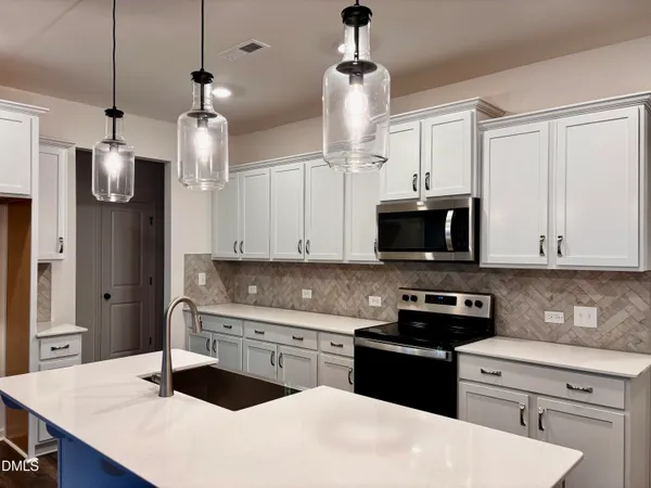 a kitchen with stainless steel appliances kitchen island granite countertop a sink a stove and a refrigerator