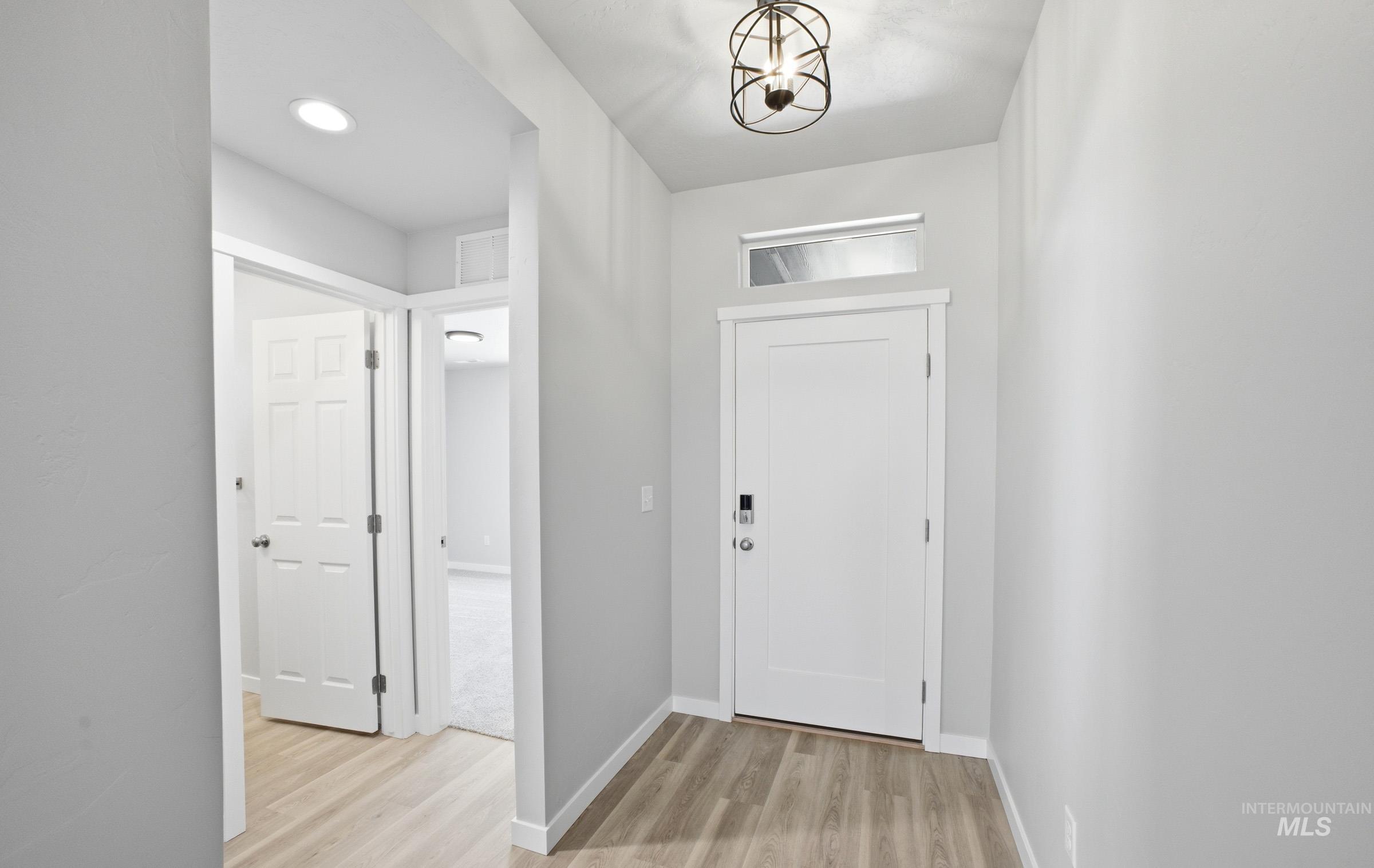 14106 Winding Street Caldwell, ID 83607 - Photo 2 of 18 Entryway featuring light wood-finish flooring, a white paneled front door with transom window, and an overhead caged light fixture