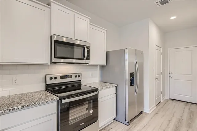 a view of kitchen with cabinets stainless steel appliances and wooden floor