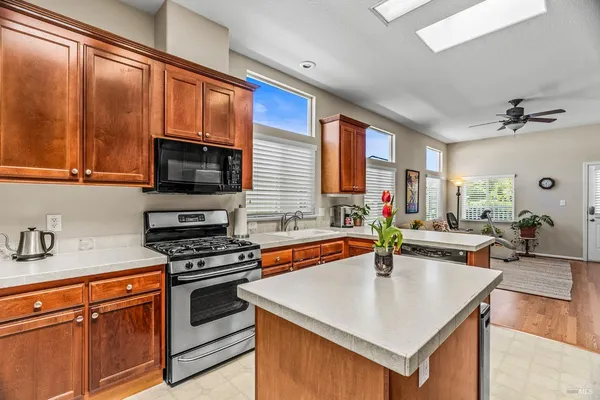 a kitchen with stainless steel appliances granite countertop a refrigerator a sink a stove a dining table and chairs with wooden floor