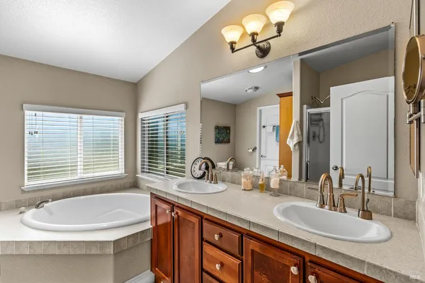 a bathroom with a tub sink double vanity and a mirror
