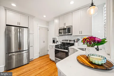 a kitchen with stainless steel appliances wooden floor and a refrigerator