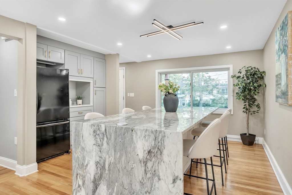38 Maple Street Lexington, MA 02420 - Photo 15 of 40 a kitchen with stainless steel appliances kitchen island granite countertop a refrigerator a oven a sink and a dining table with wooden floor