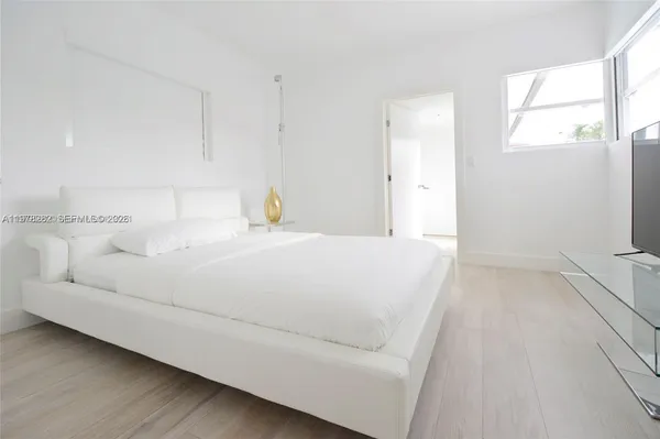 a bedroom with a white bed and a window