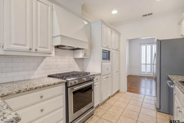 a kitchen with stainless steel appliances granite countertop white cabinets and a refrigerator