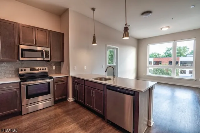 a kitchen with stainless steel appliances granite countertop a sink a stove and a wooden floors