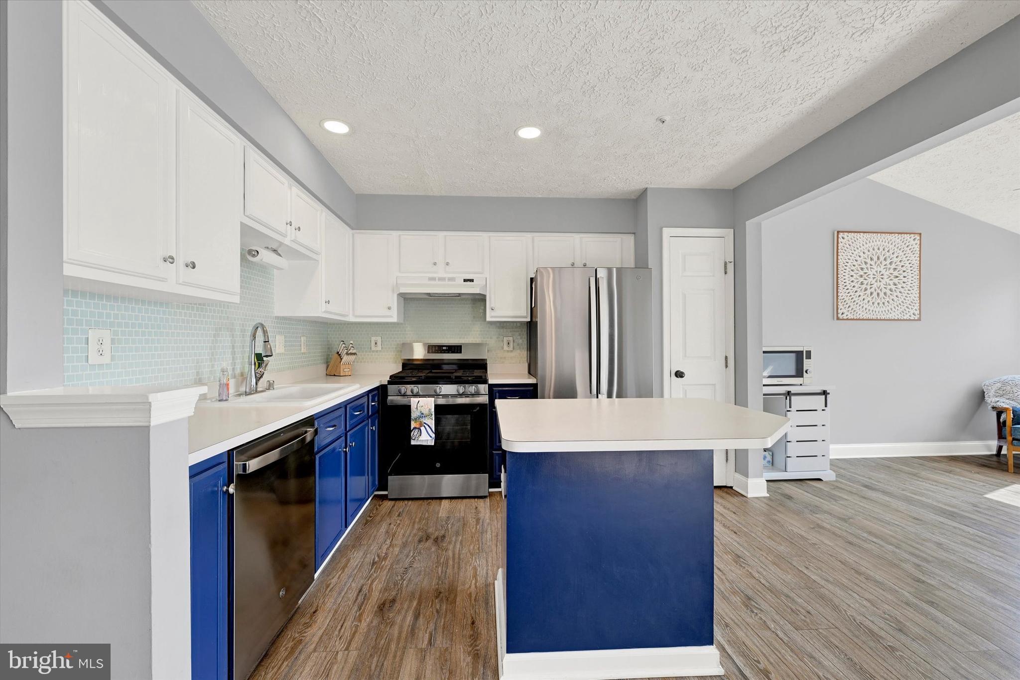 402 MacIntosh Circle Joppa, MD 21085 - Photo 10 of 29 a large kitchen with stainless steel appliances a sink dishwasher a refrigerator and white cabinets with wooden floor