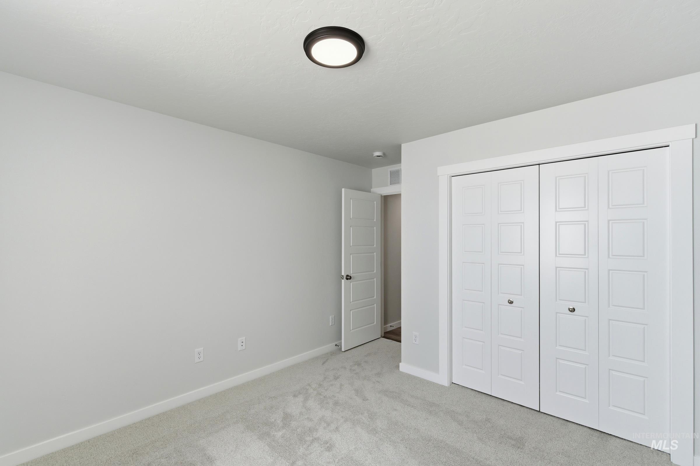 8317 South Tyrion Way Kuna, ID 83634 - Photo 16 of 22 Neutral-toned room featuring light gray walls, plush gray carpeting, and a modern flush-mount ceiling light